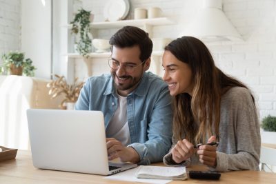 a couple looks at their bank account on their laptop computer.