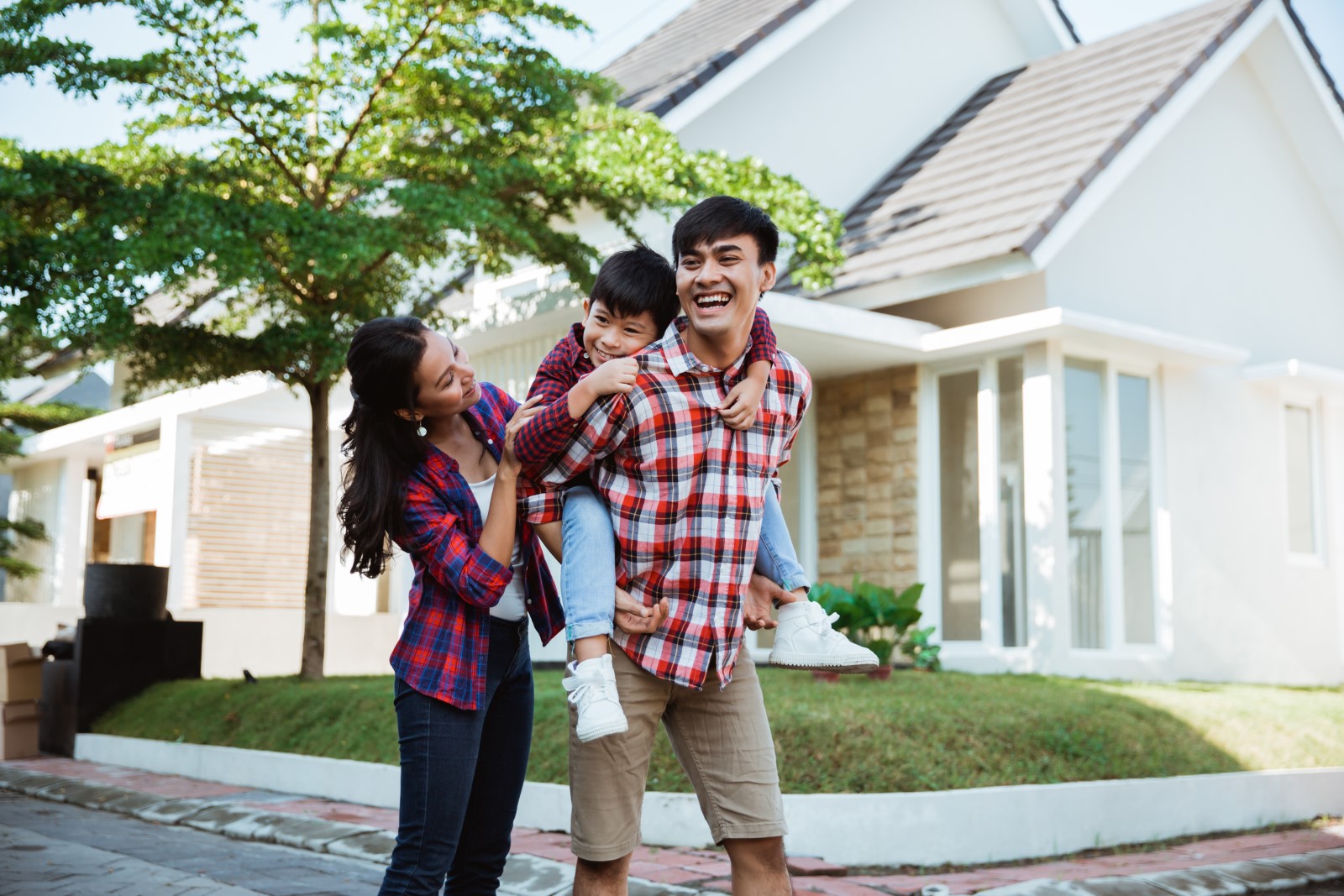 A Mom and Dad stand with their little son outside of their new home.