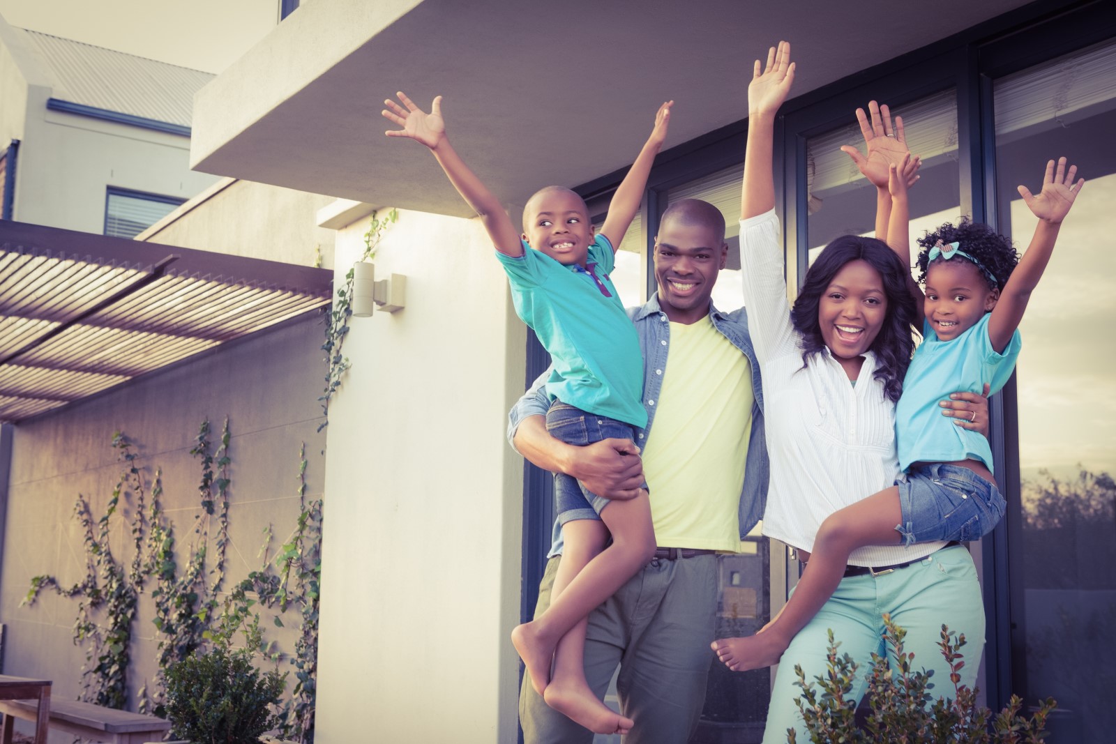 A happy family is standing in their yard celebrating their affordable mortgage refinance.